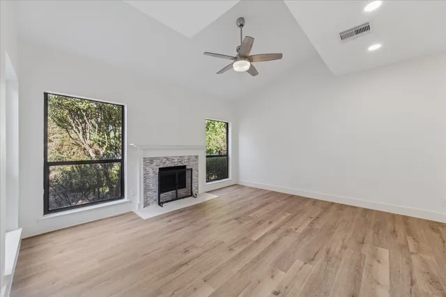 an empty room with windows fireplace and wooden floor