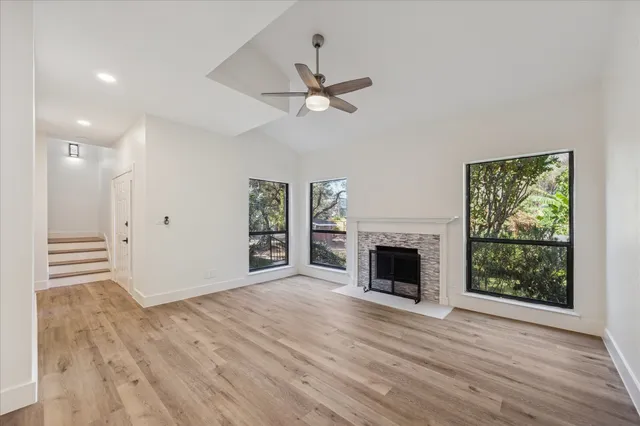 an empty room with windows fireplace and wooden floor