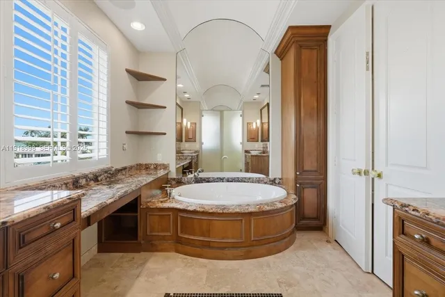a spacious bathroom with a granite countertop double vanity sink and mirror with bathtub