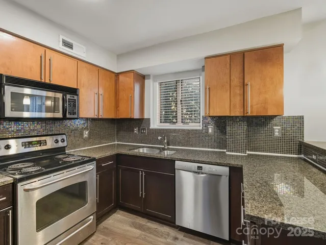 a kitchen with granite countertop a sink stainless steel appliances and cabinets