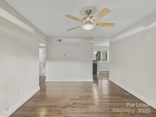 an empty room with wooden floor and hallway