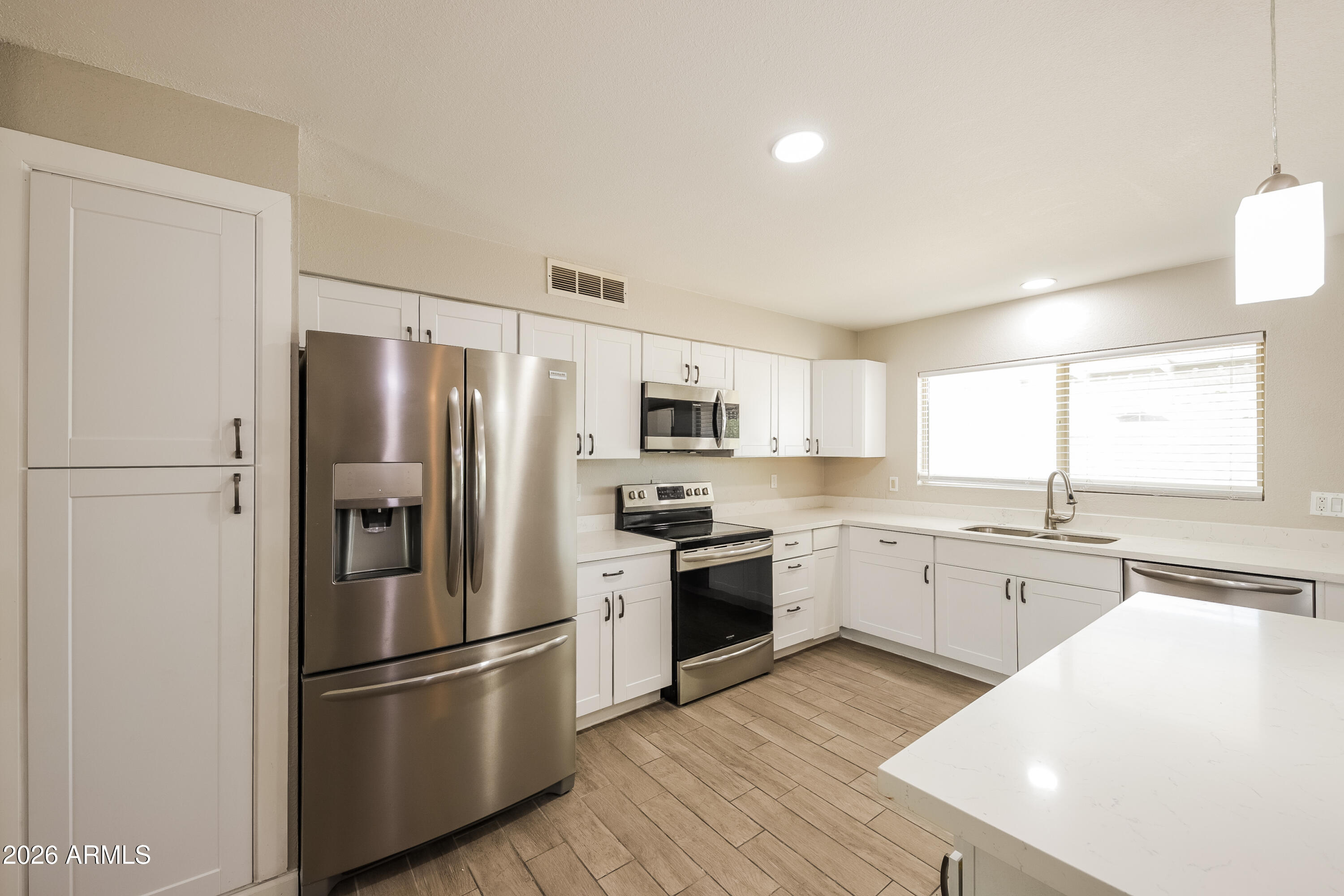 2501 East Villa Rita Drive Phoenix, AZ 85032 - Photo 10 of 15 a kitchen with stainless steel appliances granite countertop a refrigerator stove a sink and white countertops with wooden floor