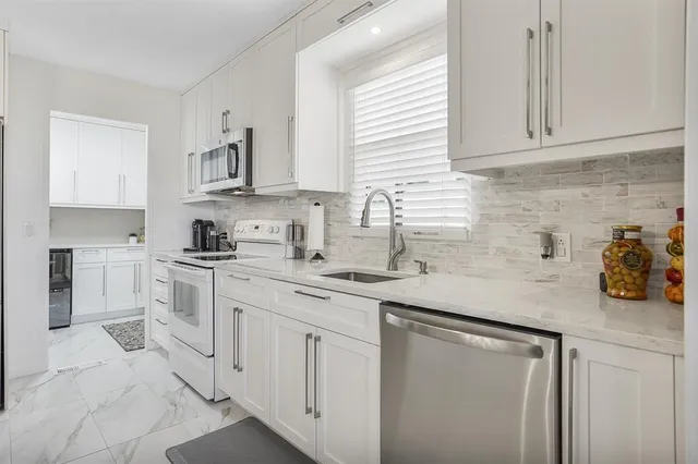 a kitchen with white cabinets and white appliances
