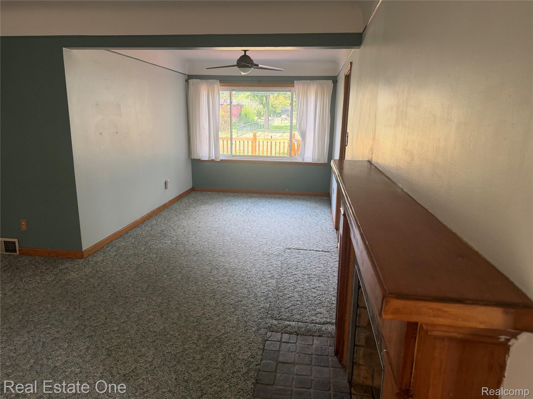 6346 Donaldson Road Troy, MI 48085 - Photo 4 of 8 Built-in fireplace with wood mantel, ceiling fan, and window with exterior fencing