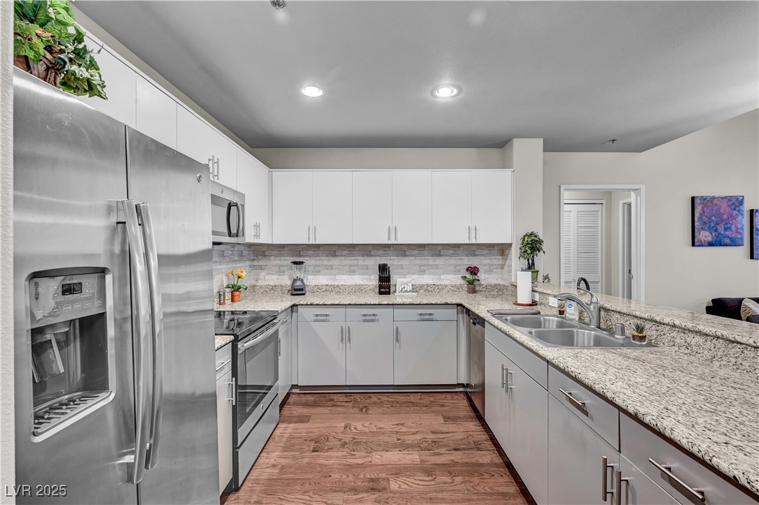 8255 South Las Vegas Boulevard, Unit 1715 Las Vegas, NV 89123 - Photo 1 of 49 Kitchen featuring stainless steel appliances, wood finished floors, backsplash, granite counters, and grey cabinetry