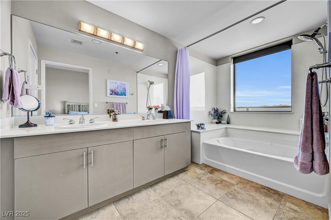8255 South Las Vegas Boulevard, Unit 1715 Las Vegas, NV 89123 - Photo 25 of 49 Spacious primary bathroom featuring double sinks, tub/shower combo, window for natural light and water closet.