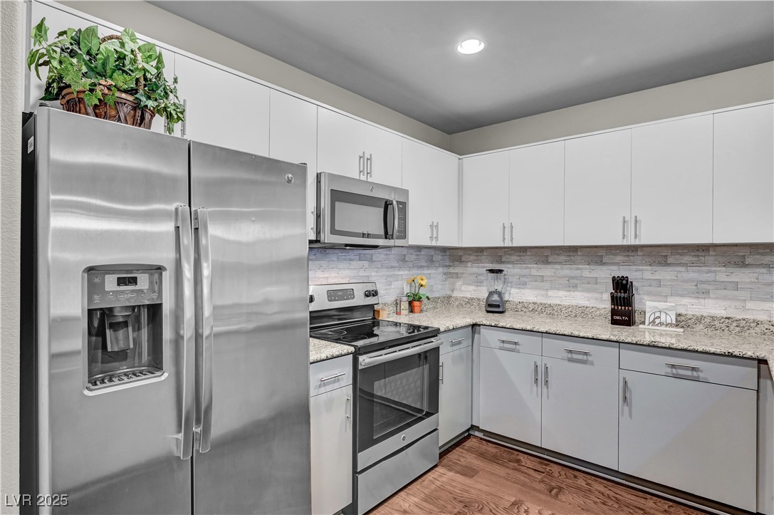 8255 South Las Vegas Boulevard, Unit 1715 Las Vegas, NV 89123 - Photo 3 of 49 Spacious kitchen featuring stainless steel appliances, wood finished floors, backsplash, granite countertops, and grey cabinetry.