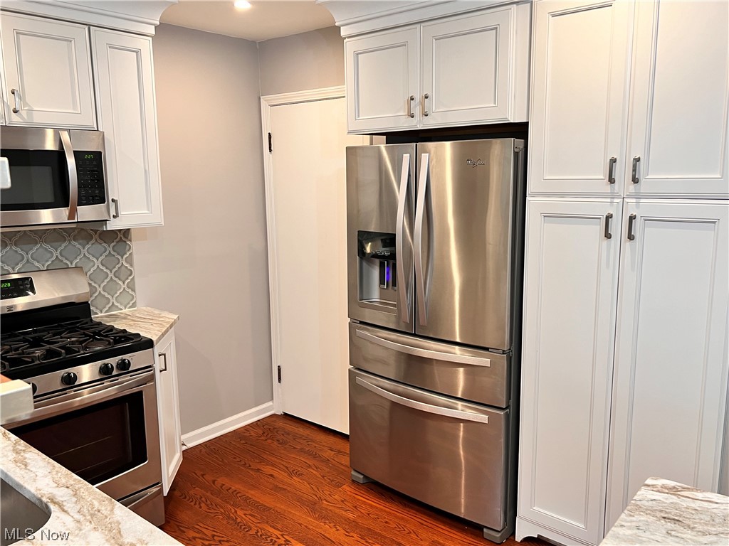 1376 Lander Road Cleveland, OH 44124 - Photo 10 of 33 Kitchen with white cabinets, light stone counters, dark hardwood floors, and appliances with stainless steel finishes