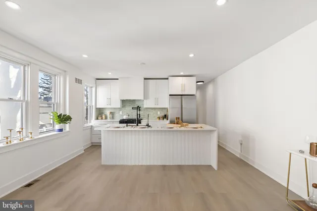a view of a kitchen with kitchen island a sink wooden floor and a large window