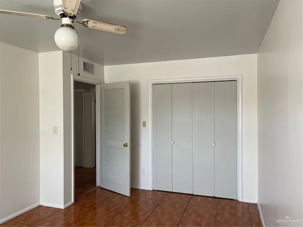 a view of an empty room with a chandelier fan