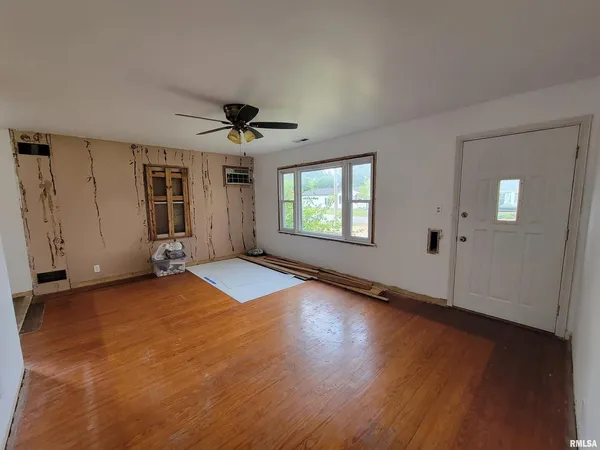 a view of an empty room with window and wooden floor