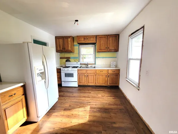 a view of a kitchen with refrigerator and wooden floor