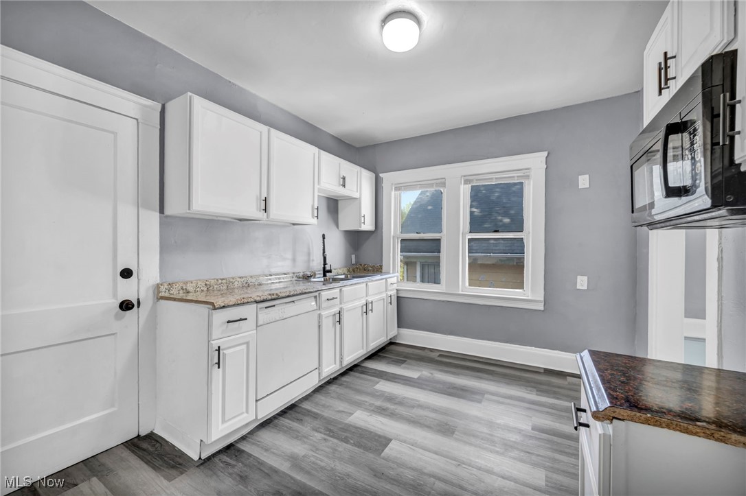 10112 Kinsman Road Cleveland, OH 44104 - Photo 24 of 49 Kitchen with white cabinetry, black microwave, white dishwasher, light wood-type flooring, and light stone counters