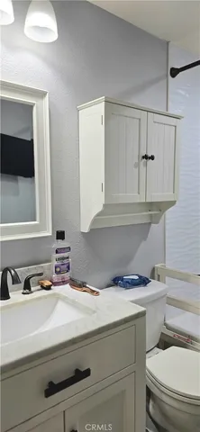 a bathroom with a granite countertop sink and a toilet