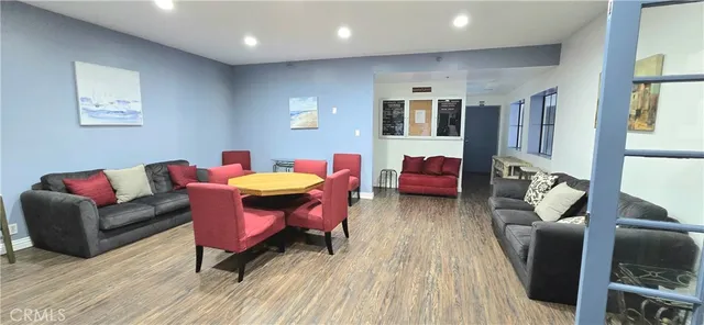 a living room with stainless steel appliances kitchen island granite countertop furniture and a wooden floor