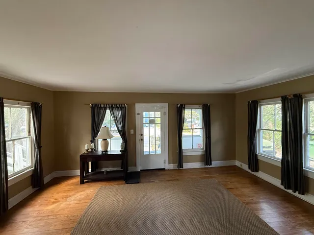 an empty room with windows and fireplace