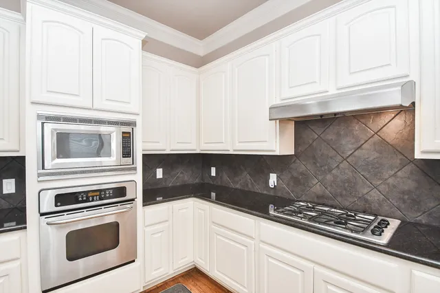 a kitchen with granite countertop white cabinets and stainless steel appliances