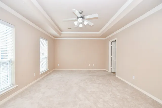 an empty room with windows and ceiling fan