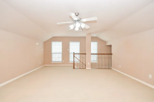an empty room with windows and ceiling fan