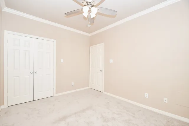 an empty room with a chandelier fan and windows