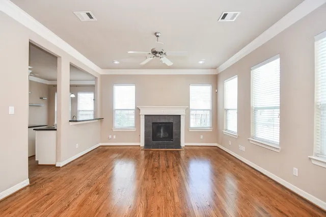 a view of an empty room with wooden floor fireplace and a window