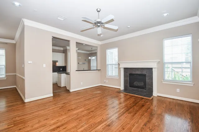 an empty room with wooden floor fireplace and windows
