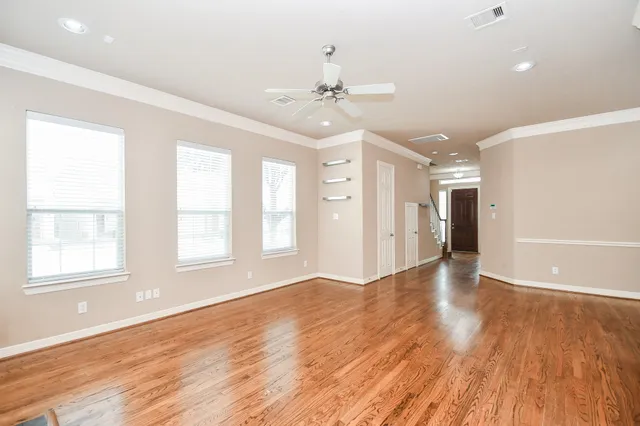 a view of an empty room with wooden floor and a window