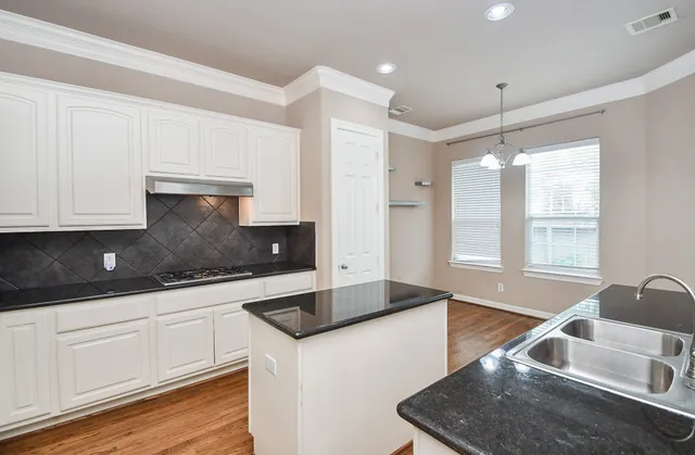 a kitchen with granite countertop a sink a stove and cabinets