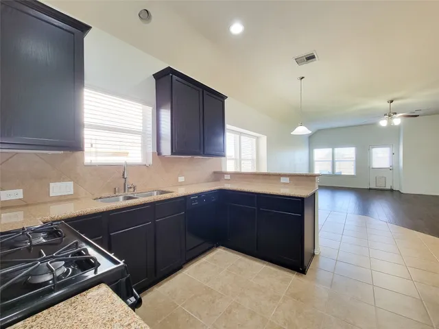a kitchen with stainless steel appliances granite countertop a sink a stove a refrigerator and a microwave