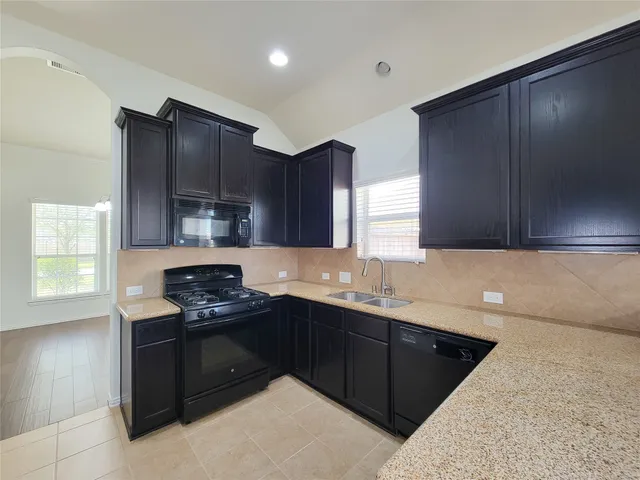 a kitchen with stainless steel appliances granite countertop a stove a sink and a microwave