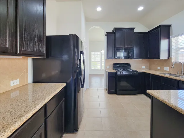 a kitchen with stainless steel appliances granite countertop a refrigerator a sink and a stove