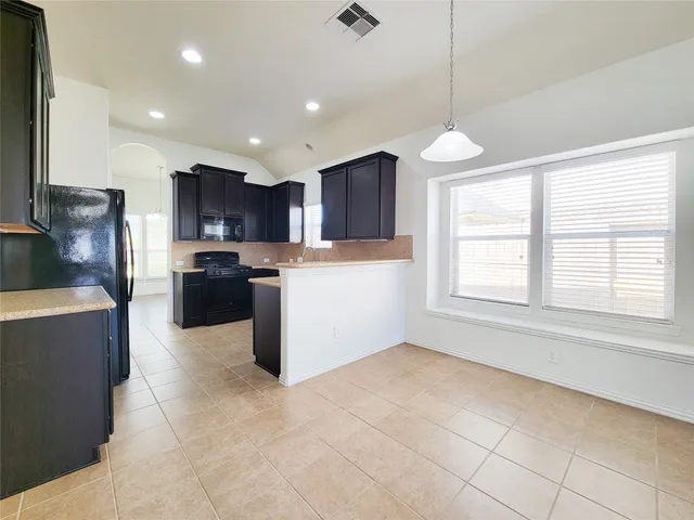 a kitchen with kitchen island granite countertop a stove top oven a sink a counter top space and cabinets