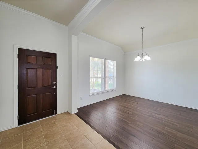 an empty room with wooden floor cabinet and windows