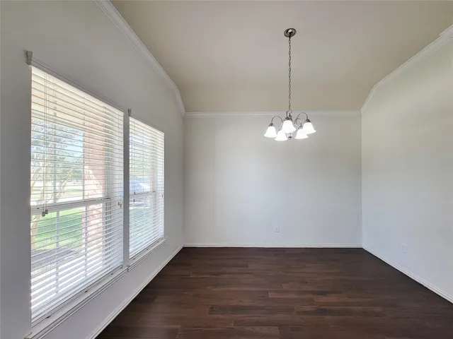 a view of a room with wooden floor chandelier and windows