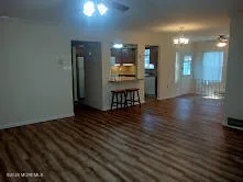 a view of a room with wooden floor and a kitchen