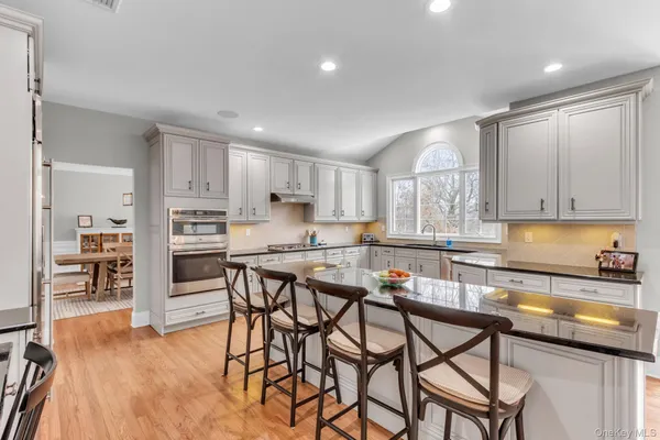 a kitchen with stainless steel appliances kitchen island granite countertop a table chairs sink and cabinets