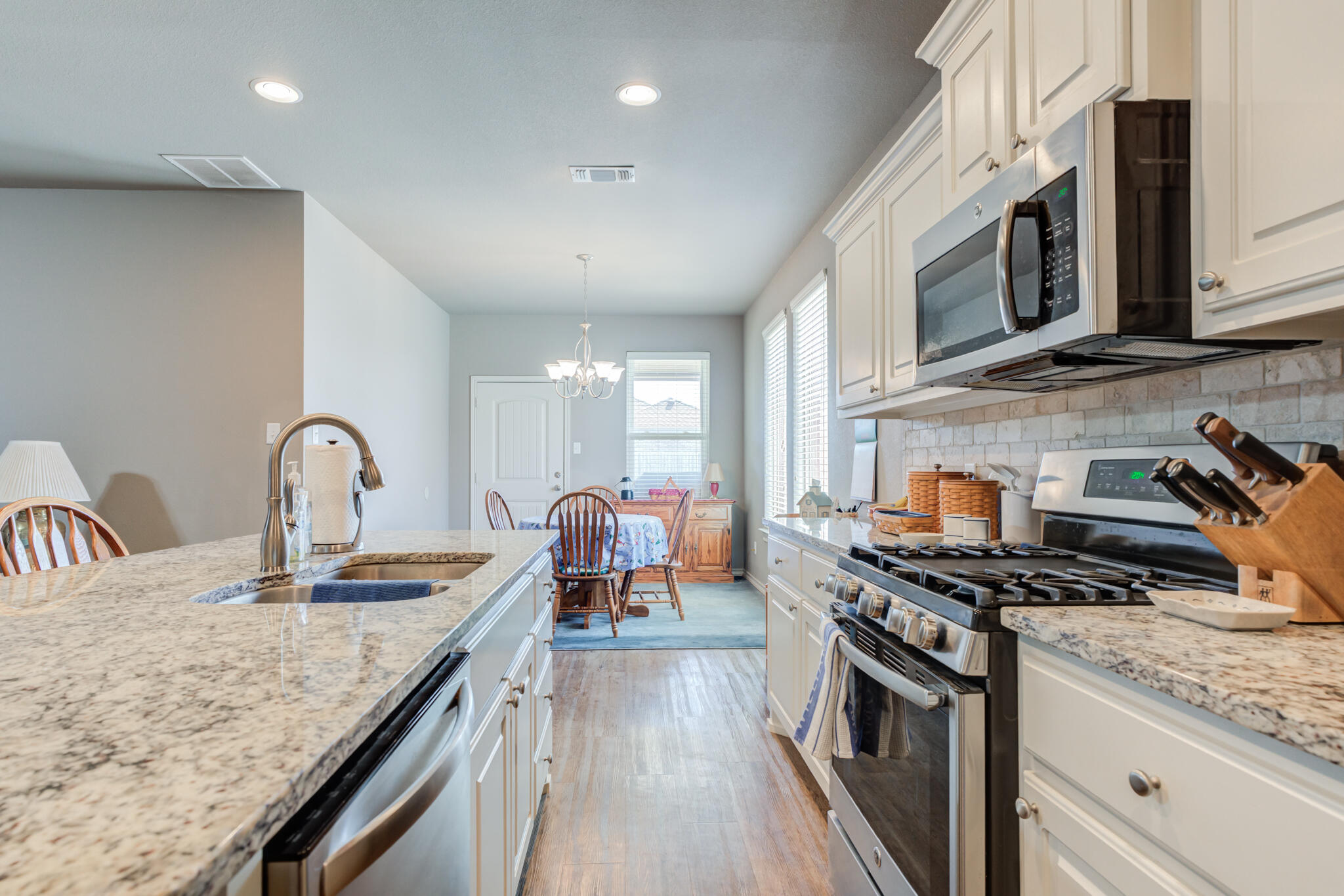 5219 Kemper Street Lubbock, TX 79416 - Photo 16 of 38 a kitchen with stainless steel appliances granite countertop a stove a sink and a microwave