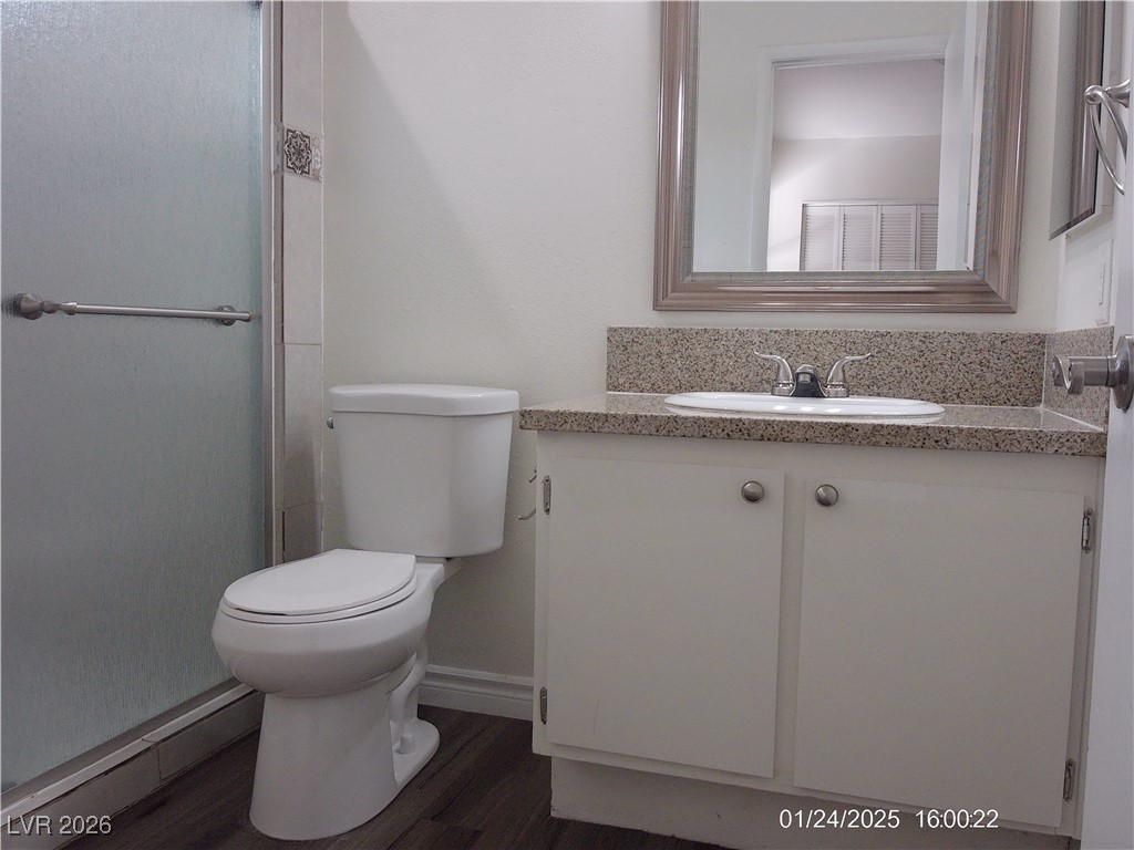 7313 Saybrook Point Drive Las Vegas, NV 89128 - Photo 16 of 31 Full bathroom featuring vanity, dark wood-style flooring, and a shower with shower door