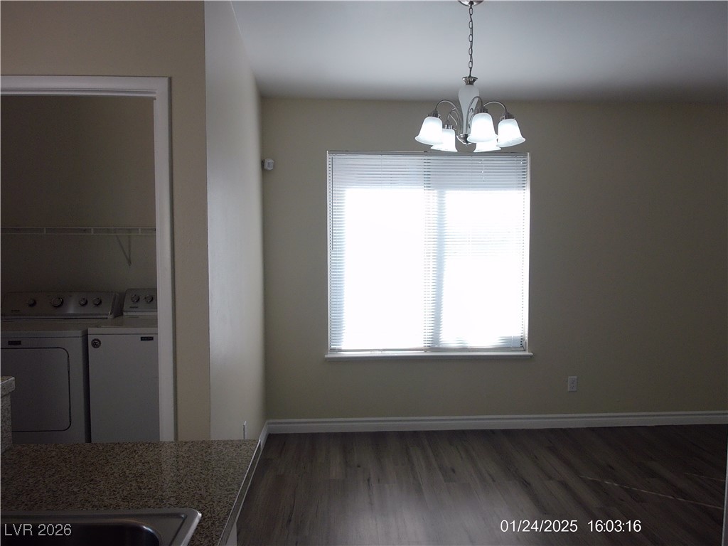 7313 Saybrook Point Drive Las Vegas, NV 89128 - Photo 8 of 31 Unfurnished dining area with dark wood-style flooring, washing machine and clothes dryer, and a chandelier