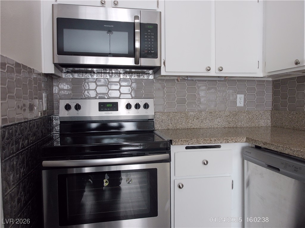 7313 Saybrook Point Drive Las Vegas, NV 89128 - Photo 10 of 31 Kitchen with stainless steel appliances, white cabinets, decorative backsplash, and dark stone counters
