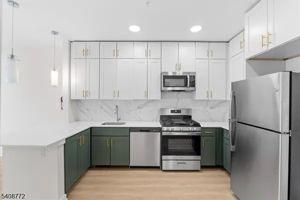 a kitchen with stainless steel appliances a stove a sink a refrigerator a window and white cabinets