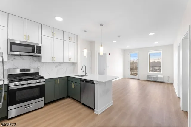 a kitchen with a sink a microwave a refrigerator and white cabinets