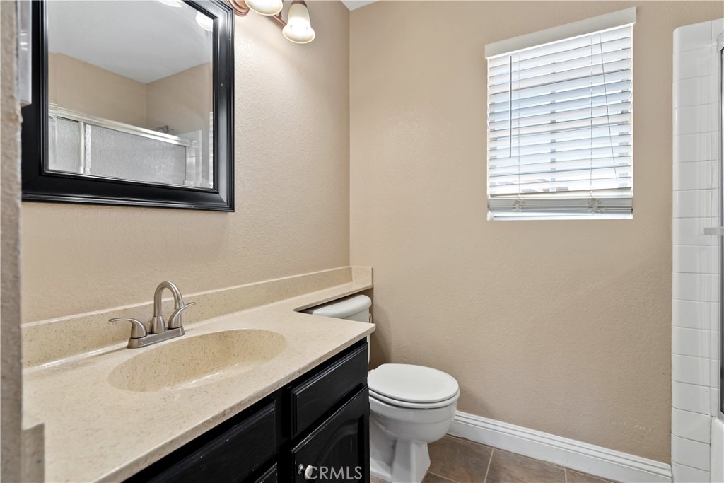 9321 Loquat Drive Riverside, CA 92508 - Photo 31 of 39 a bathroom with a toilet a sink and mirror