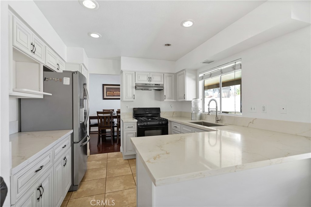 9321 Loquat Drive Riverside, CA 92508 - Photo 10 of 39 a large white kitchen with granite countertop a large window and stainless steel appliances