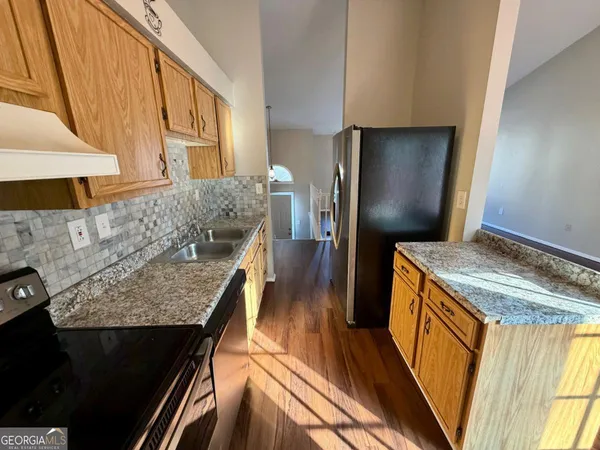 a kitchen with granite countertop a stove a refrigerator and wooden floor