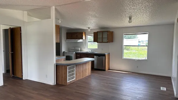 a kitchen with stainless steel appliances granite countertop a sink a stove a refrigerator and a window