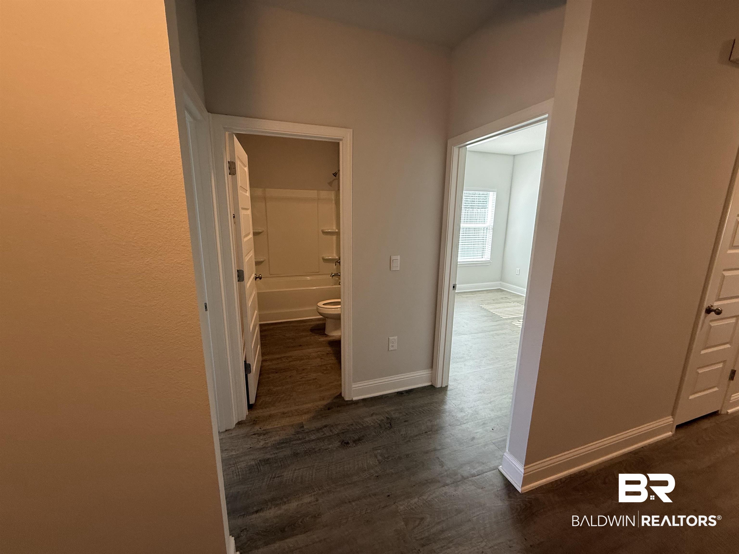 23247 Lieutenant Avenue Foley, AL 36535 - Photo 4 of 47 Hallway featuring wood-finish flooring, crisp white baseboards, and neutral wall tones