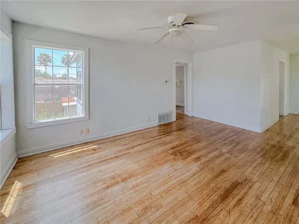 a view of empty room with wooden floor and fan