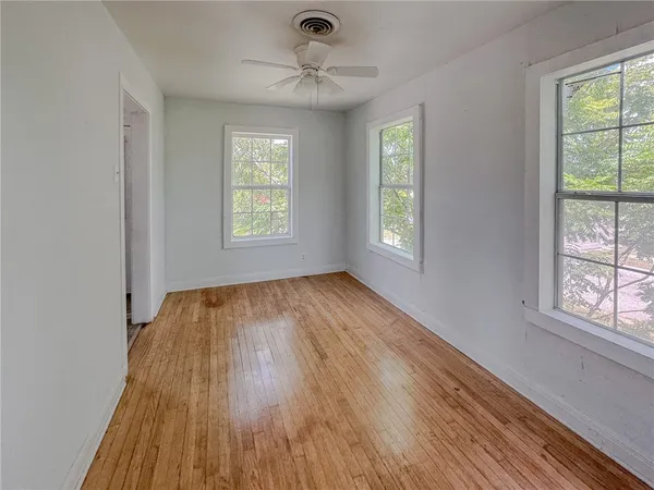 a view of an empty room with wooden floor and a window