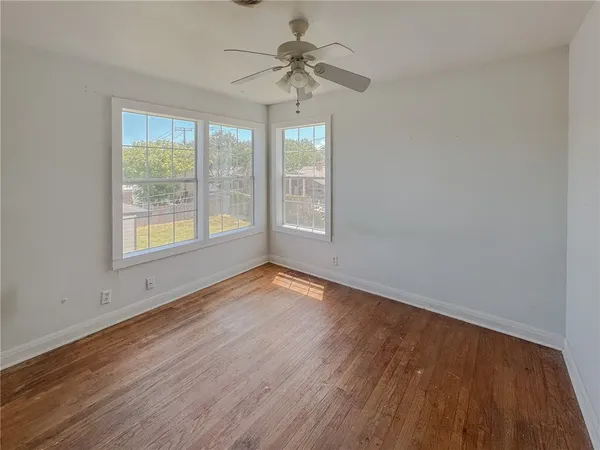a view of an empty room with a window and wooden floor